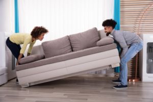 A young millennial couple smiles as they place furniture in their new house or apartment