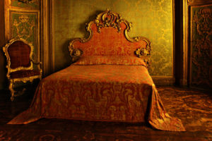 an old red and gold bed lays almost untouched
