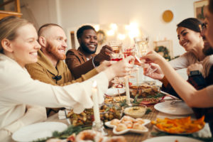 Group of people raising glasses sitting at beautiful dinner table celebrating Christmas with friends and family.