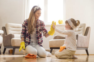A woman and little girl high-five each other as they finish up cleaning the hardwood floor of their home for the spring season. 